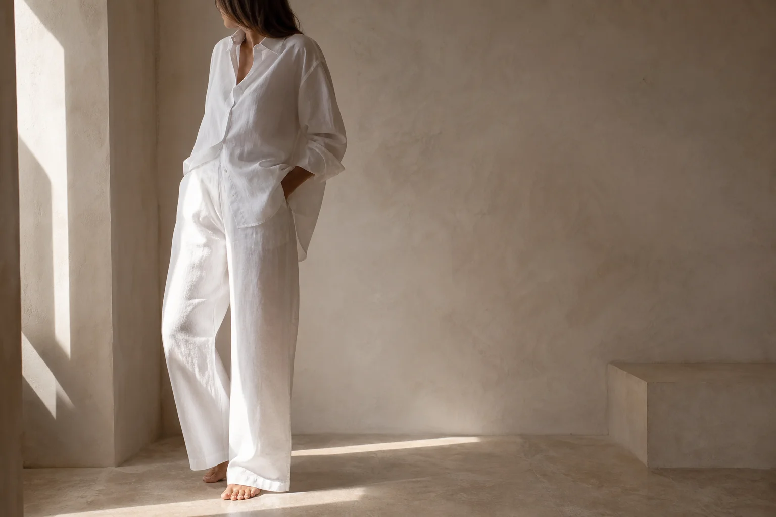 Model in a white poplin shirt and linen trousers in a sunlit room