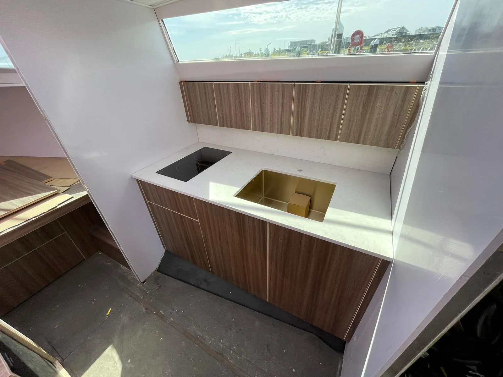 Galley taking shape — stone benchtop, gold sink, induction cooktop