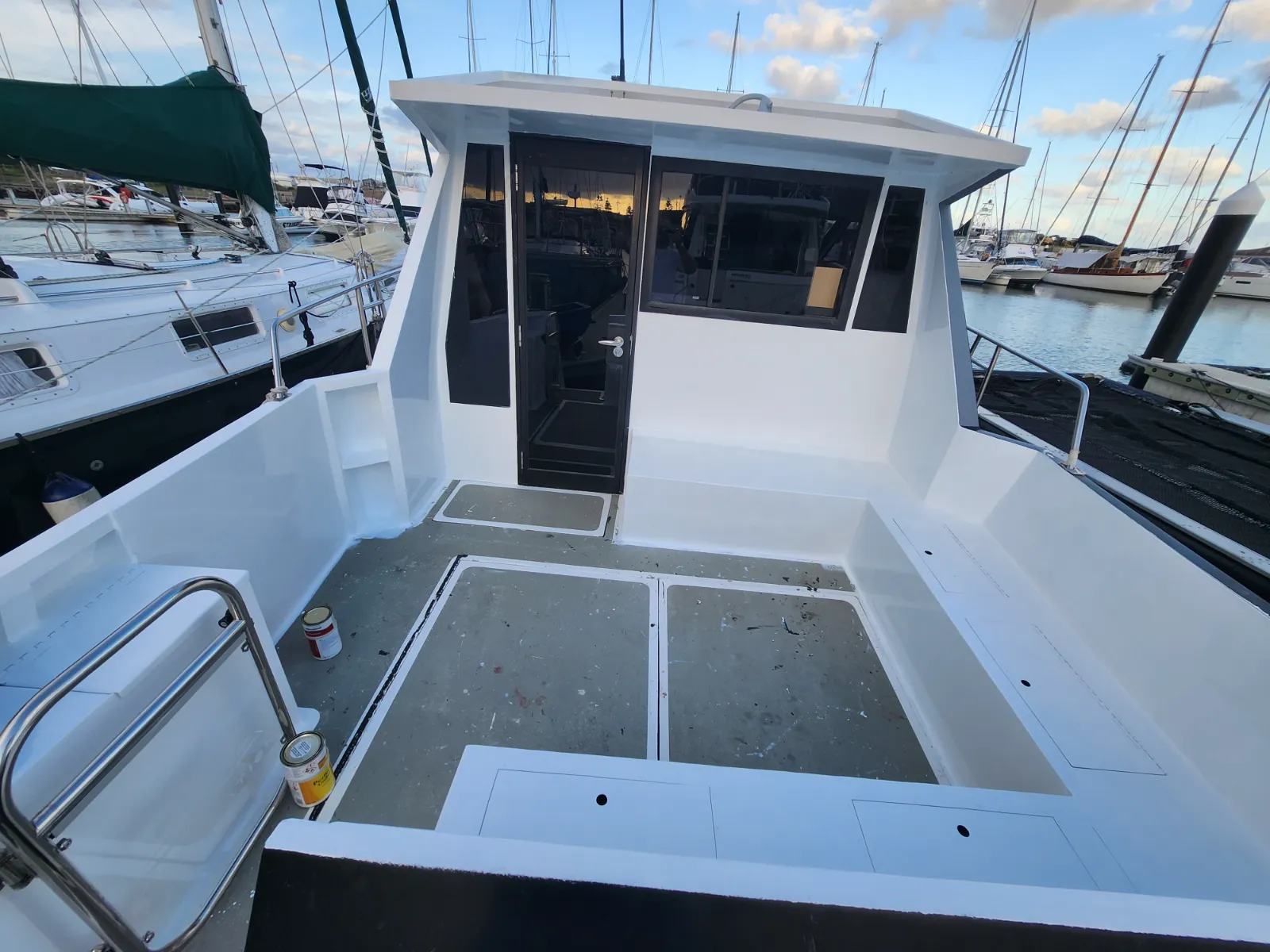 Cockpit and aft deck before teak — bare grey paint, hatches in place
