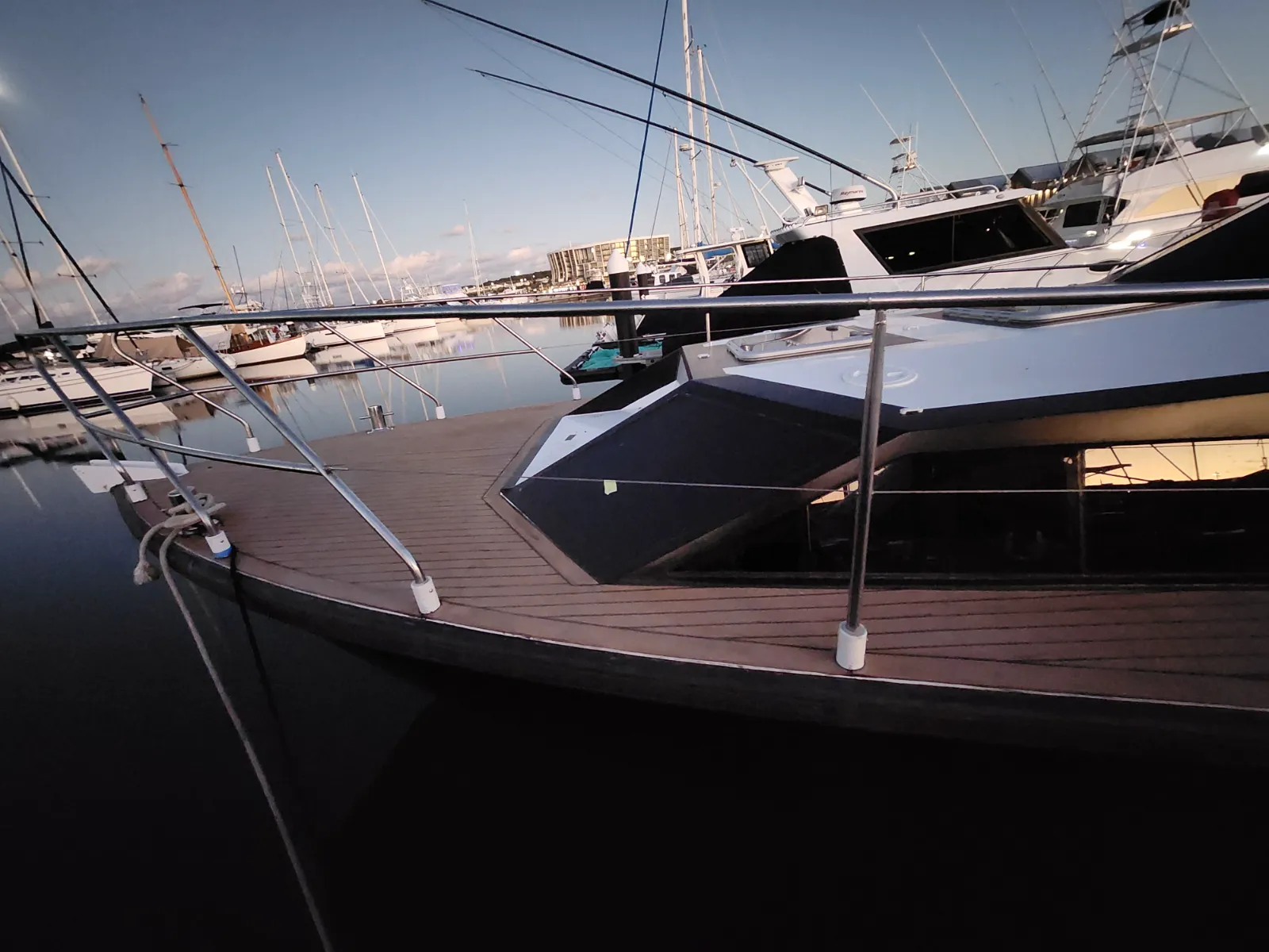Teak decking laid along the side deck at dusk — marina in background