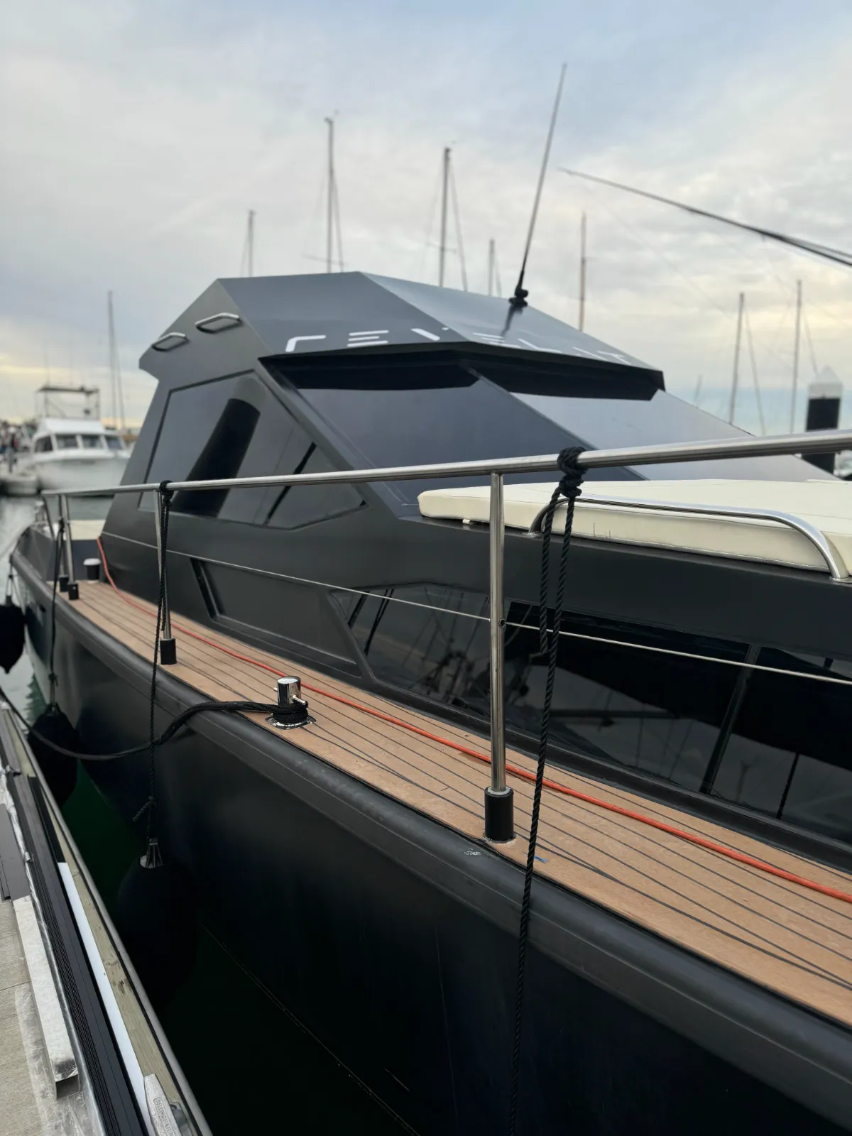 Revelation side deck — satin black hardtop and hull with teak decking, moored at marina
