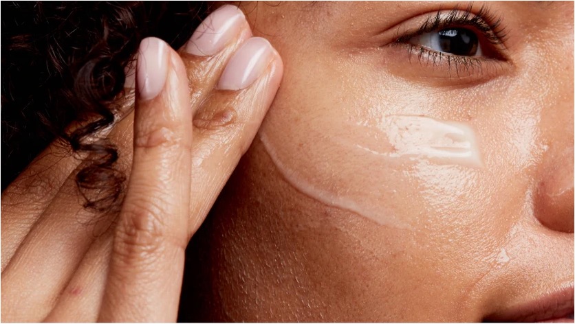 Woman gently pressing a peptide serum into her cheek, demonstrating topical absorption into skin.