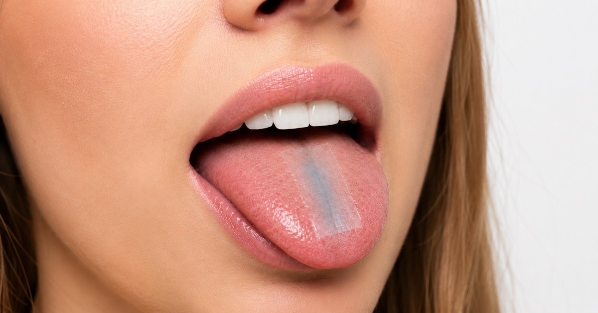 Close-up of an oral strip placed on a tongue, showing sublingual peptide delivery.