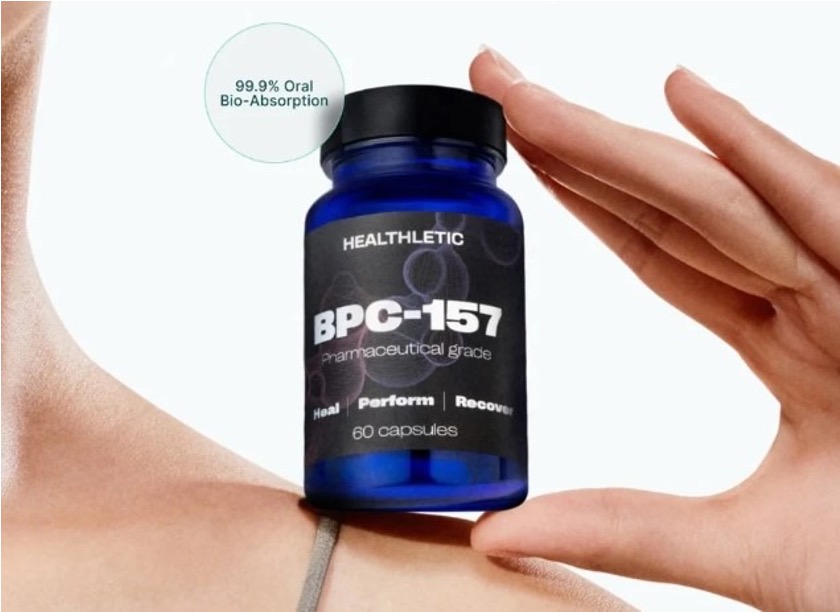 Hand holding a dark blue bottle of Healthletic BPC-157 capsules, 60-count, labeled pharmaceutical grade