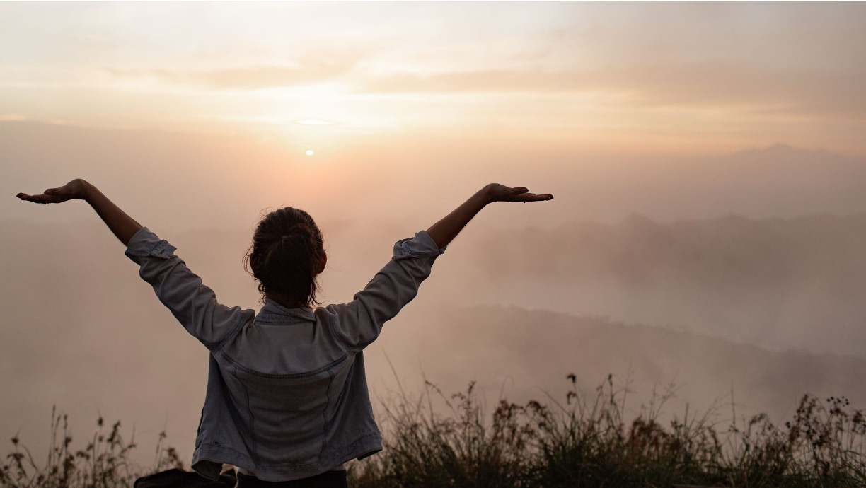 Woman standing outdoors at sunrise.