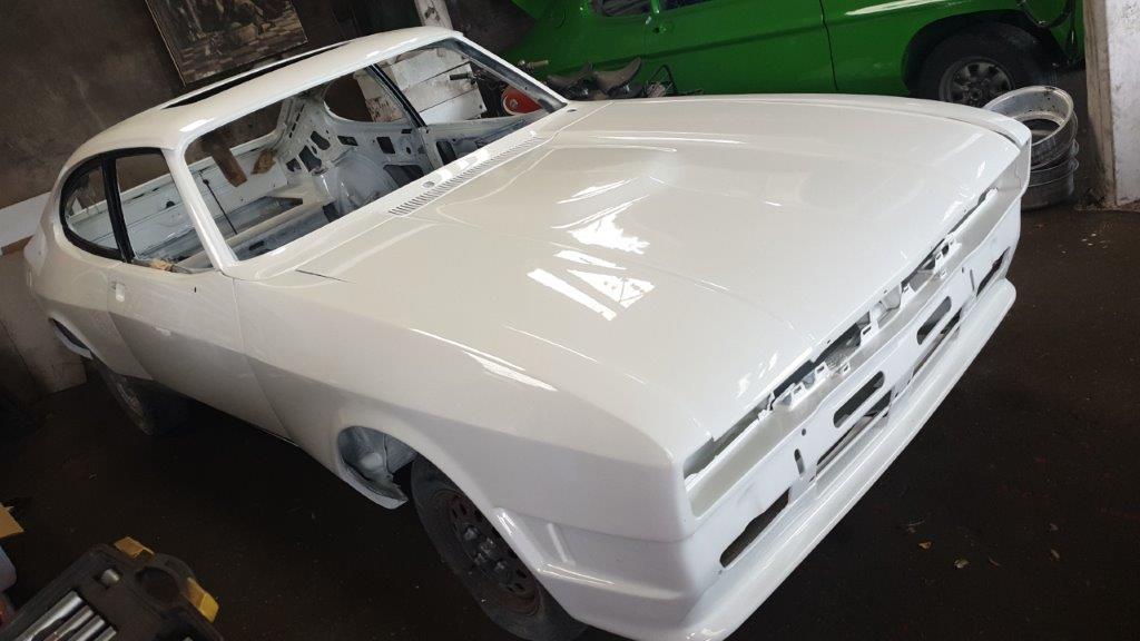 The freshly painted white Capri shell back in the workshop, rear three-quarter view