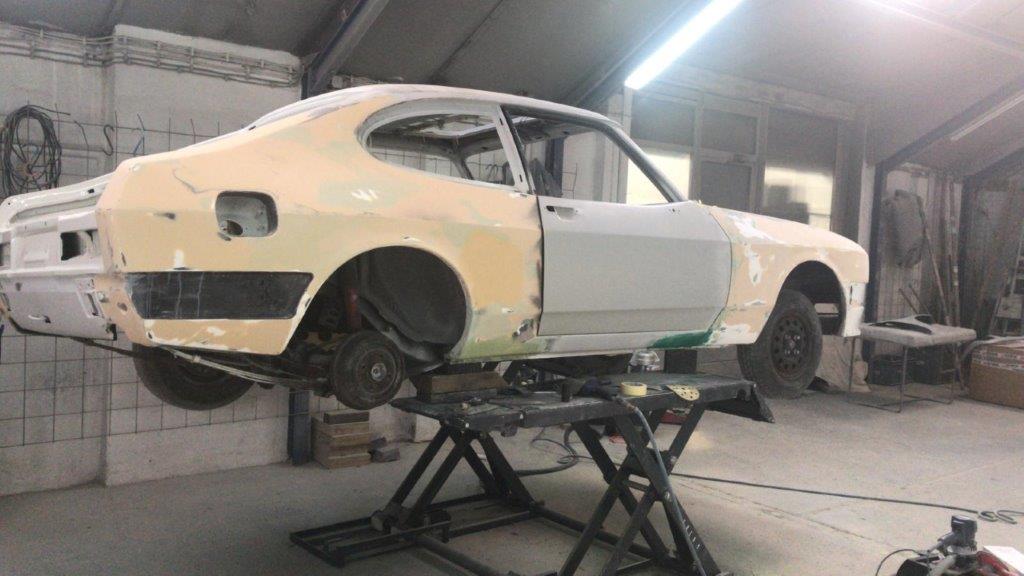 The stripped Ford Capri 3.0 RS Special raised on the workshop lift, filler and primer visible across the panels