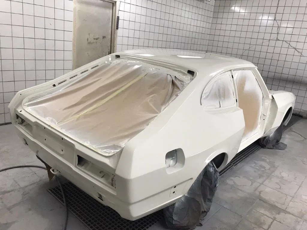 The Capri shell masked up in the spray booth, rear three-quarter view