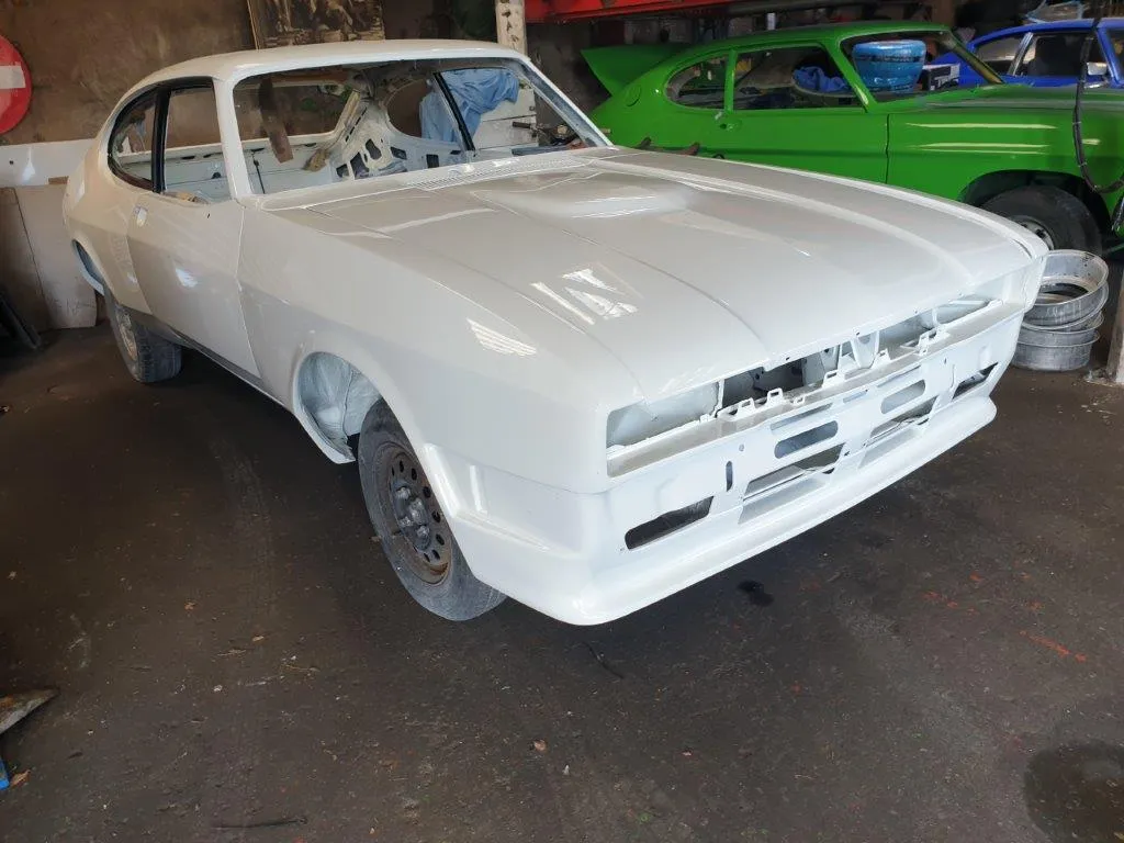 The freshly painted white Capri shell in the workshop, front three-quarter view