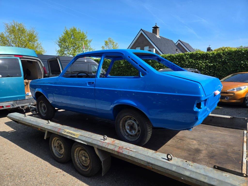 The Escort in blue paint loaded on the trailer, side view