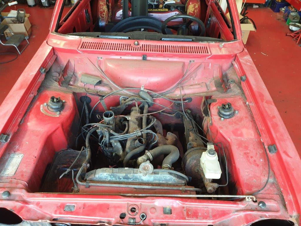 The engine bay of the red Ford Escort Mk2 as found, bonnet open