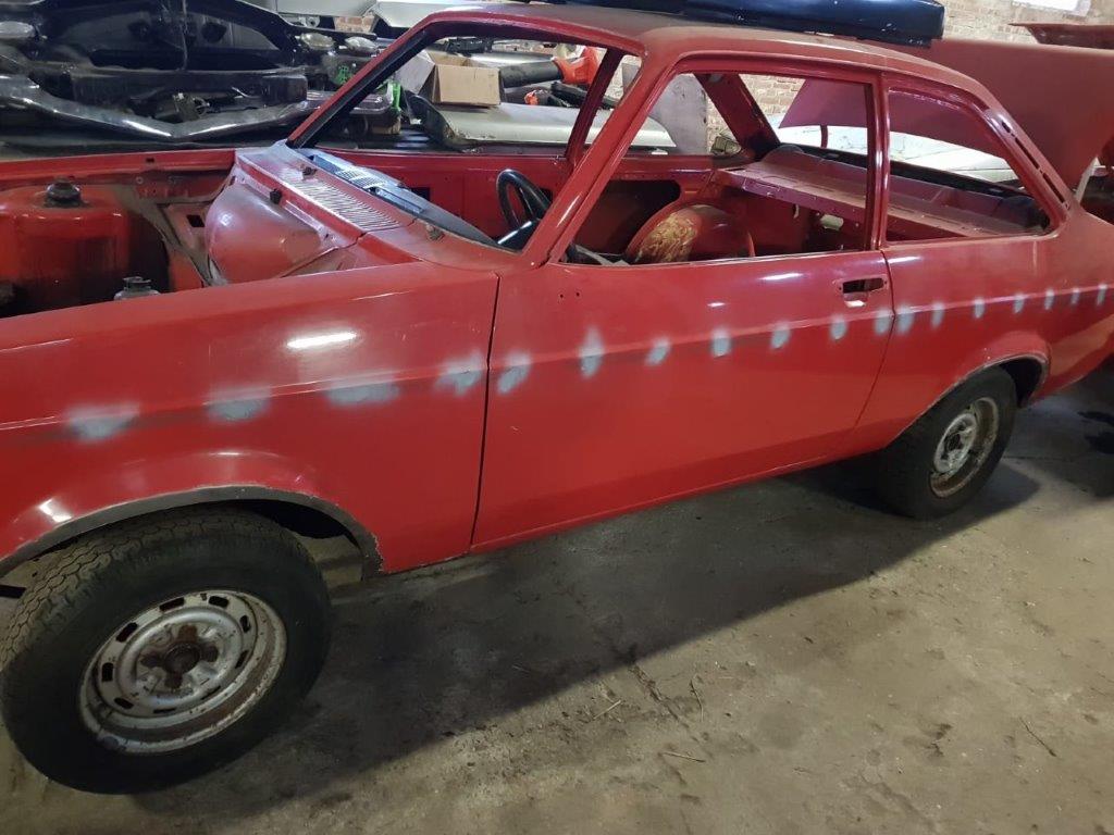 The stripped red Escort with the roll cage in place and the doors removed