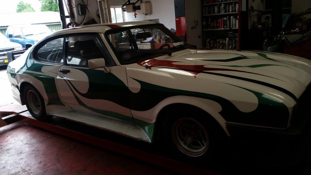 The finished Ford Capri 2.8 Werksturbo in its white livery with green and red striping, indoors