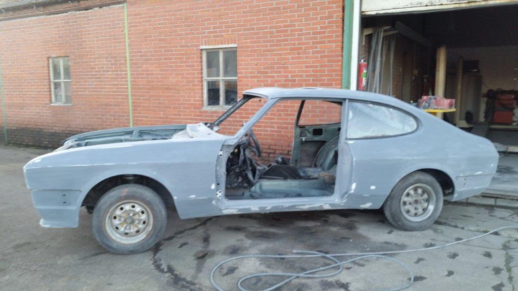 The Capri shell in primer alongside the workshop, side view