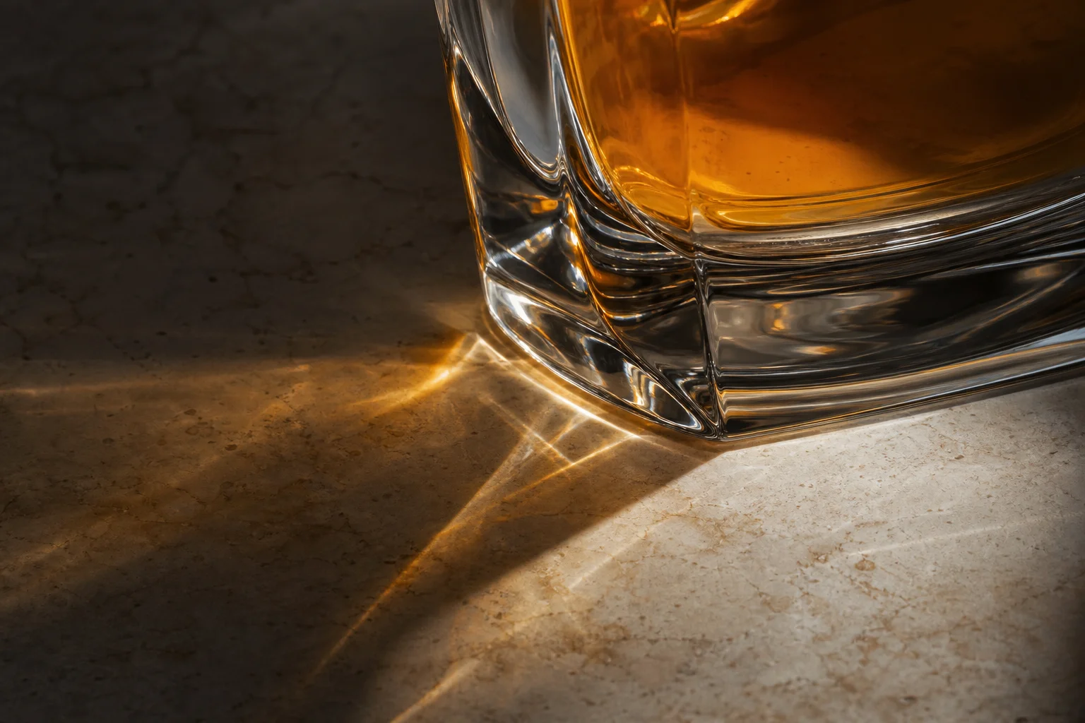 Warm amber liquid and a glass edge catching light in an editorial fragrance still life