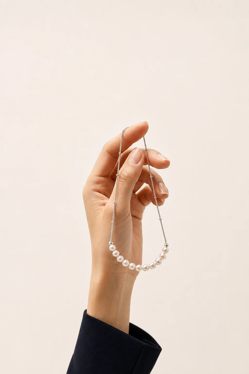 A hand gently holding Novraya’s Luna pearl necklace
