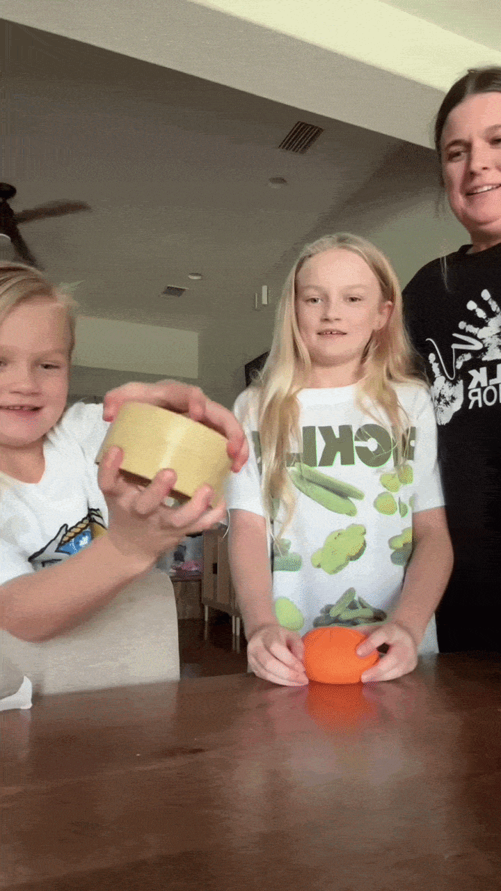 Two kids squishing dumplings at the kitchen table