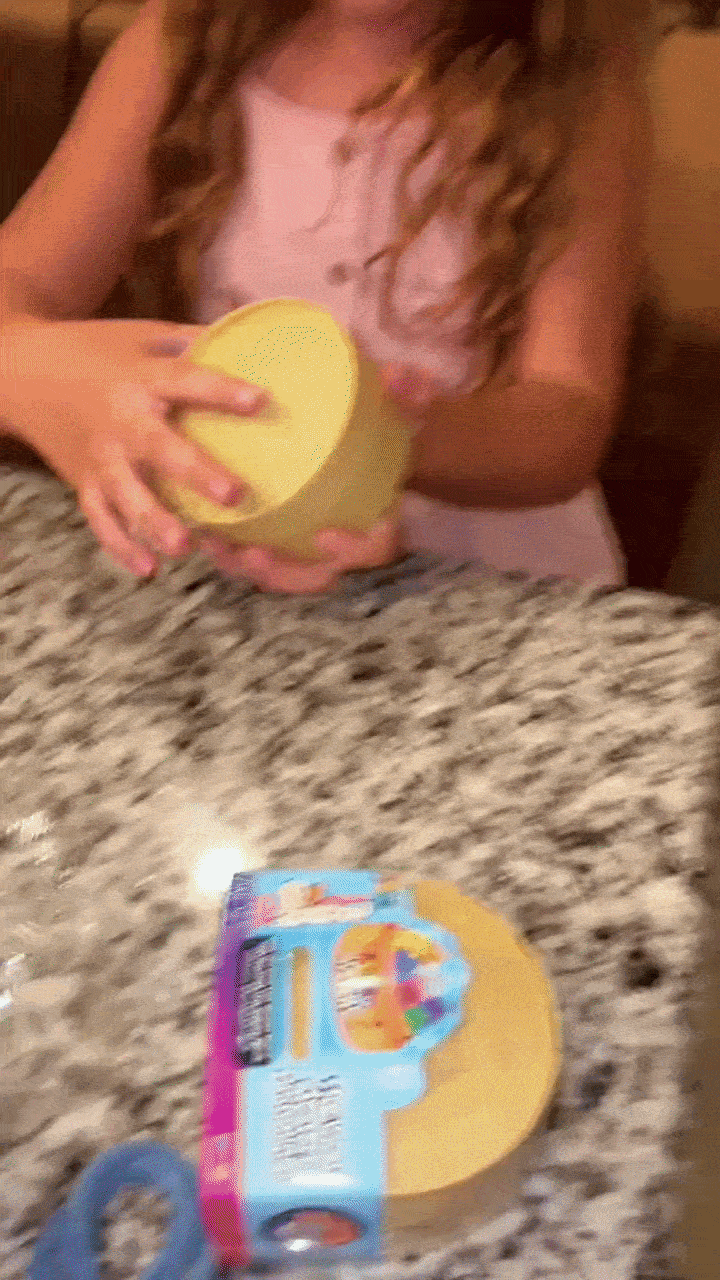 Kid shaking a steamer basket to guess the mystery color inside