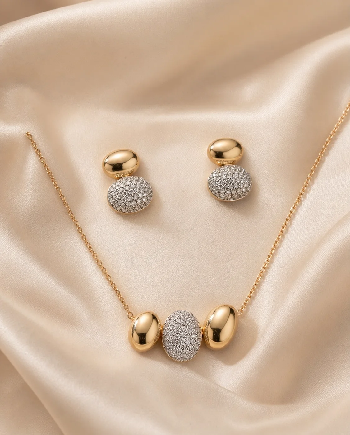 Colar e par de brincos com formas ovais em tom dourado e detalhes brilhantes.