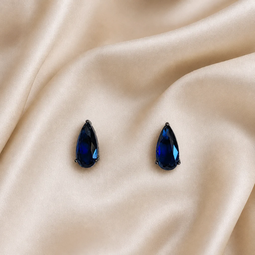 Pedra azul profunda em formato de gota, presa por garras em metal escuro.