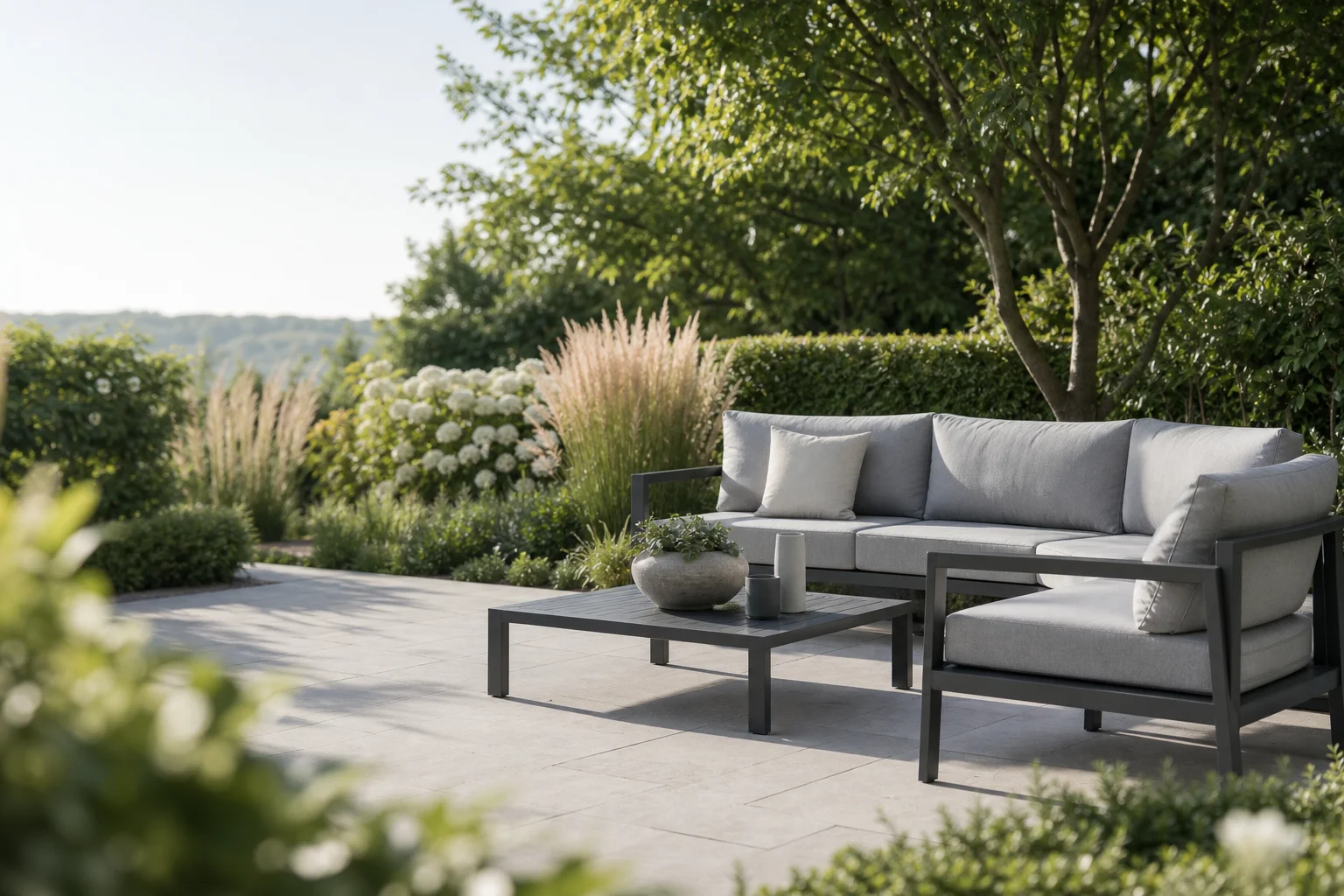 Modern garden patio with an aluminium lounge set surrounded by greenery
