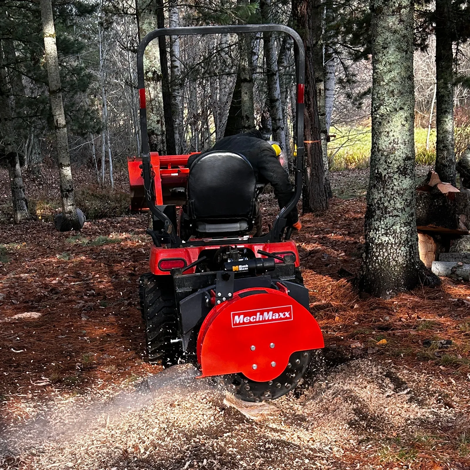 The SG24 mounted on a compact tractor grinding a stump among the trees