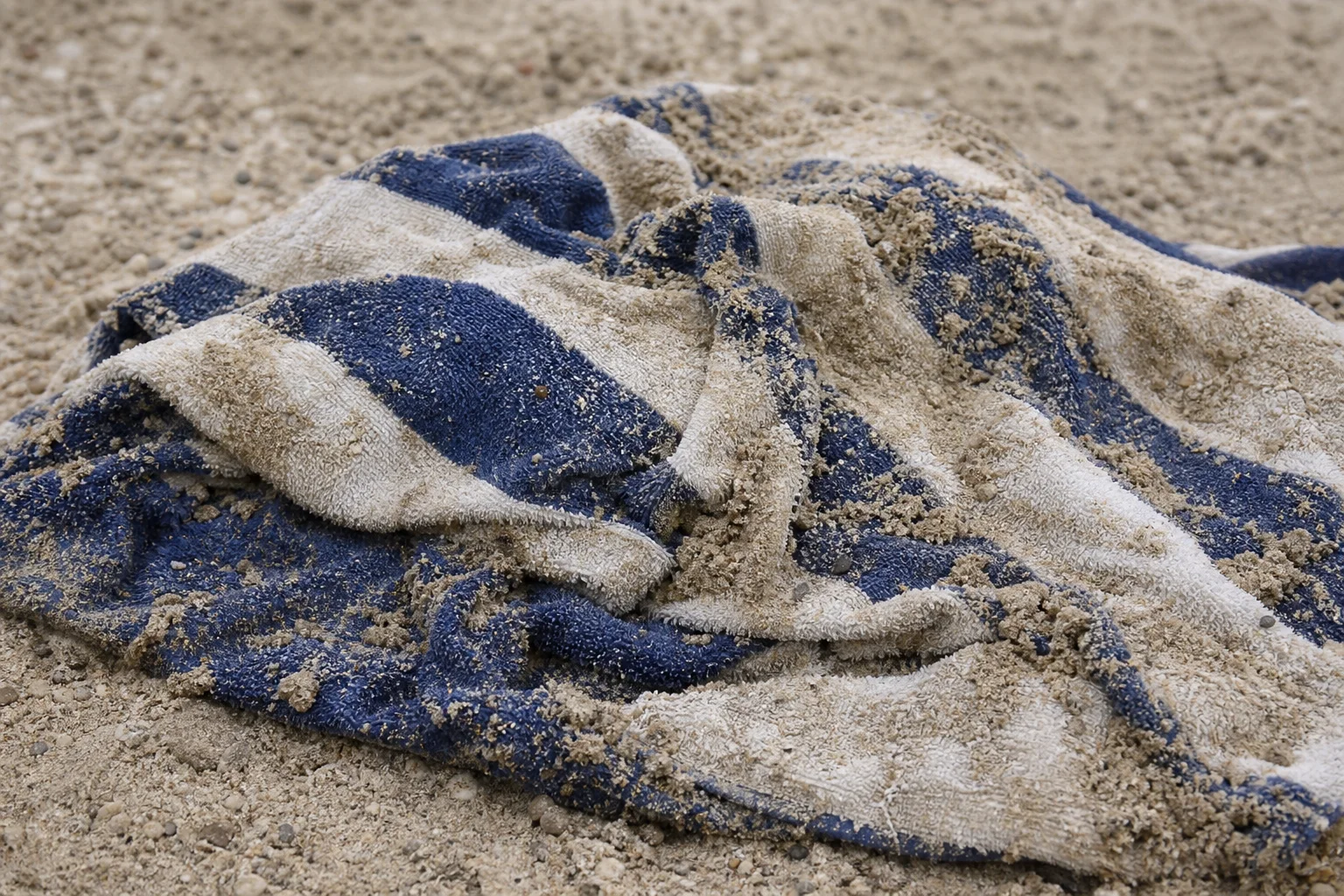 Ordinary beach towel soggy and clumped with sand