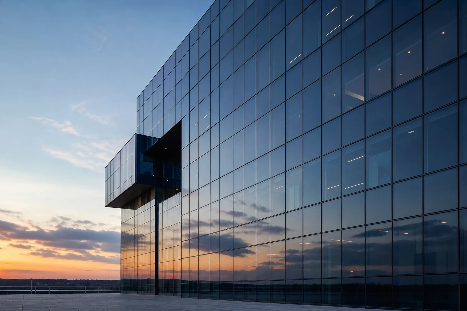 The glass façade of a modern office building reflecting the sky at dusk