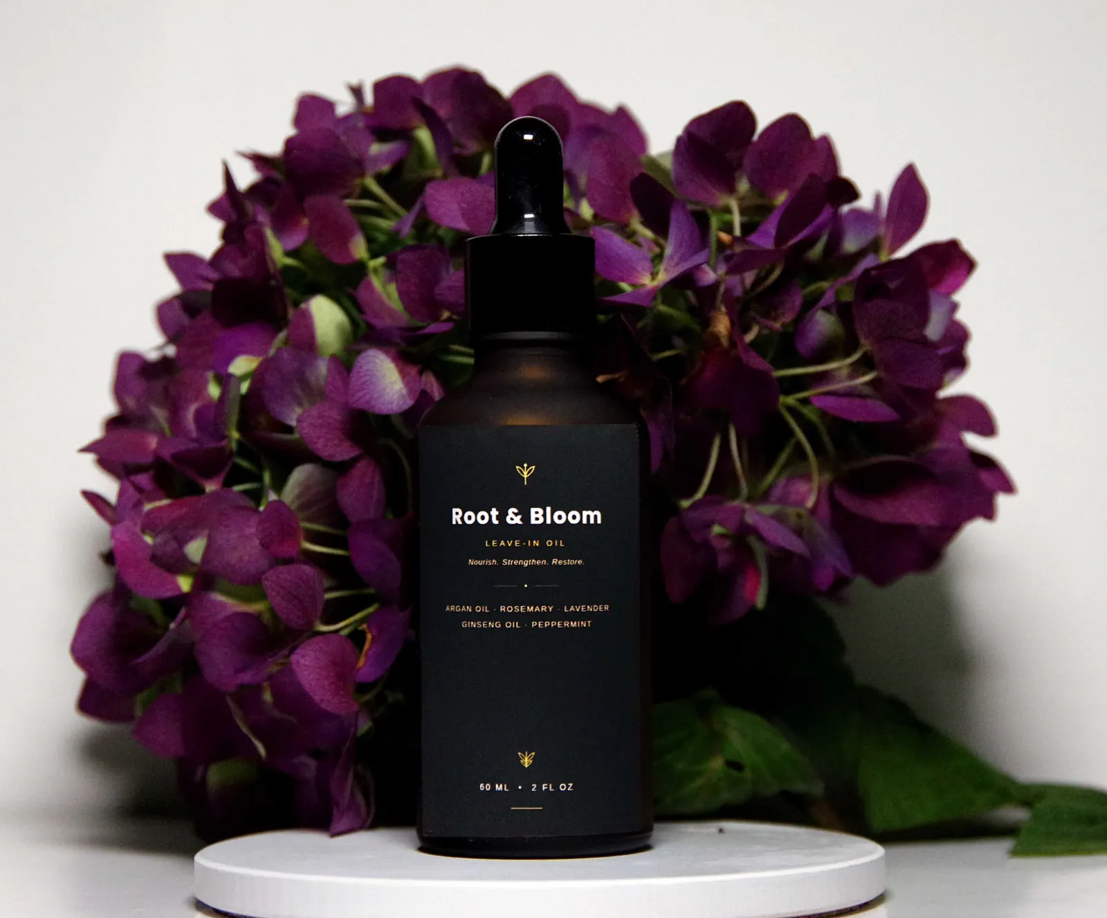 Root and Bloom hair treatment bottle framed by deep purple hydrangeas
