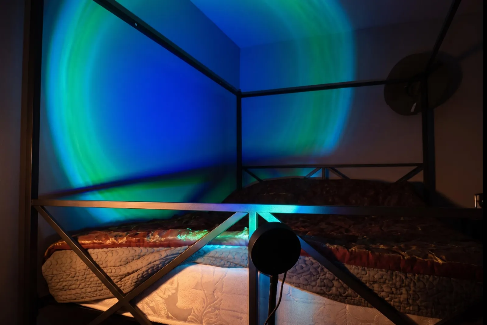 Aqua Wave Table Lamp casting blue and green light across a bedroom