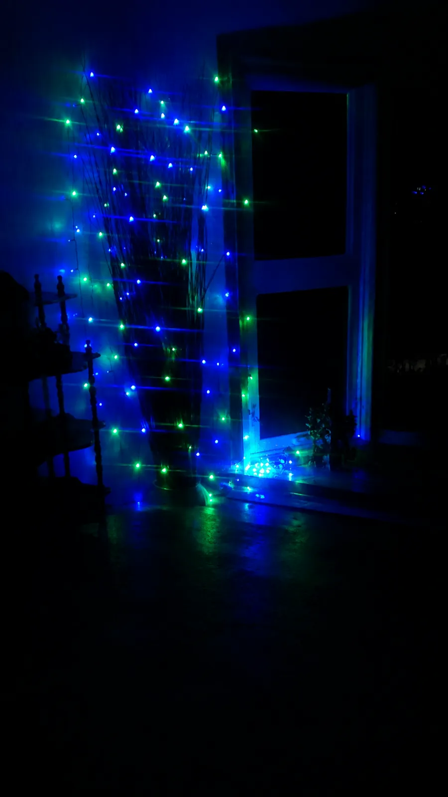 Blue and green hanging lights arranged around a doorway at night